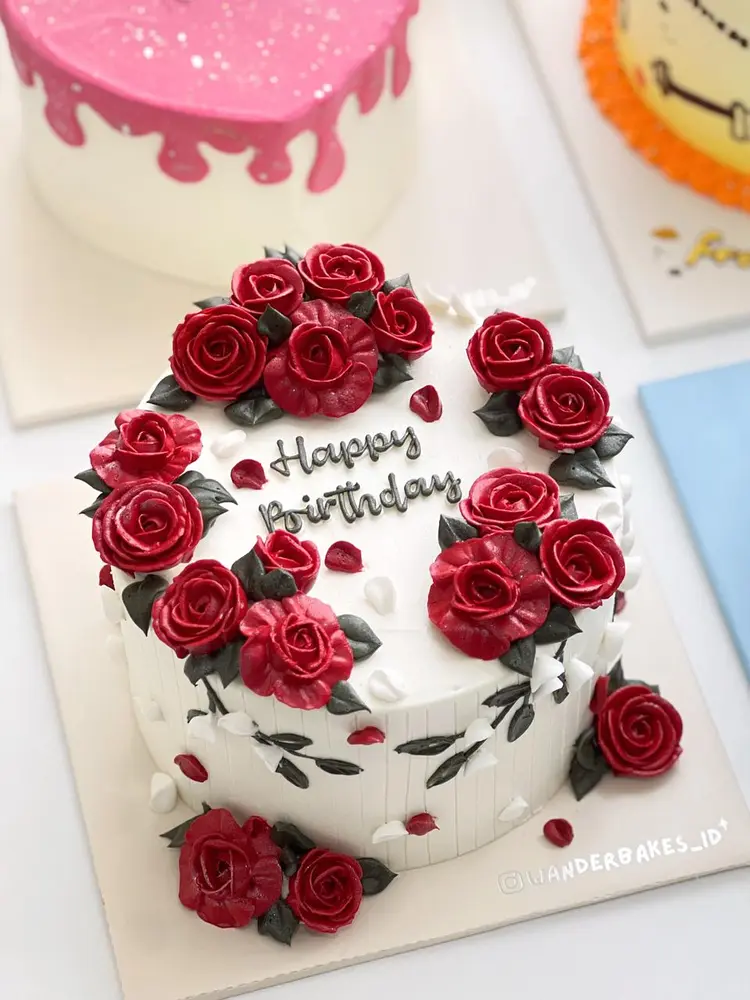Cake putih dengan mawar buttercream merah dan tulisan Happy Birthday