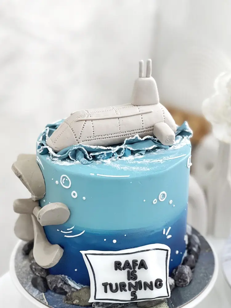 Cake biru laut dengan kapal selam fondant di atasnya